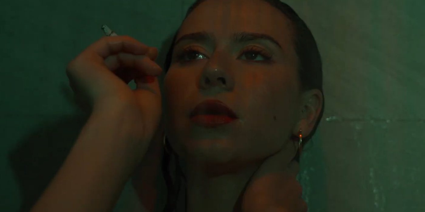 Film still: under green light in a shower, cigarette in hand