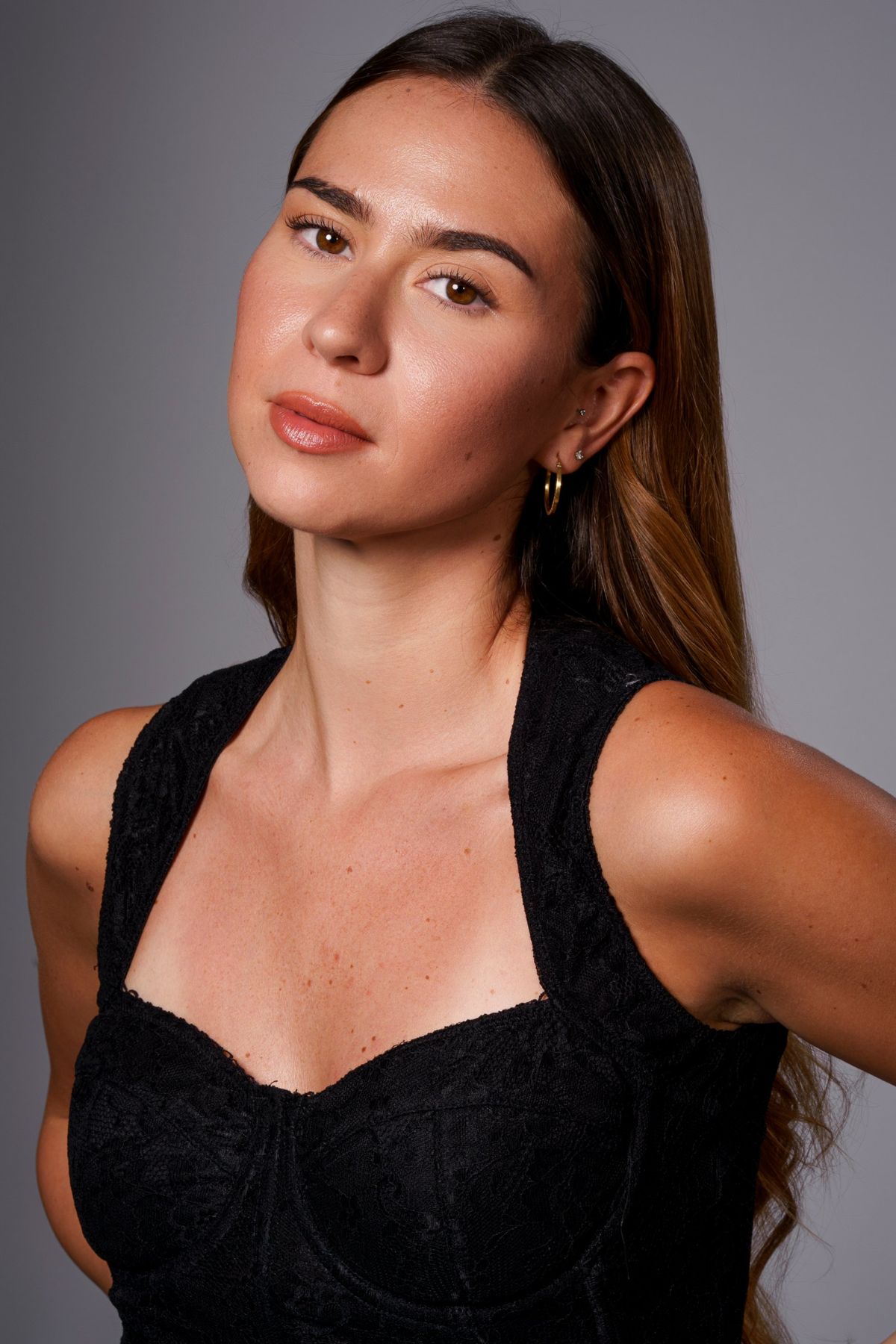 Headshot in black lace, head tilted, gold hoop earring