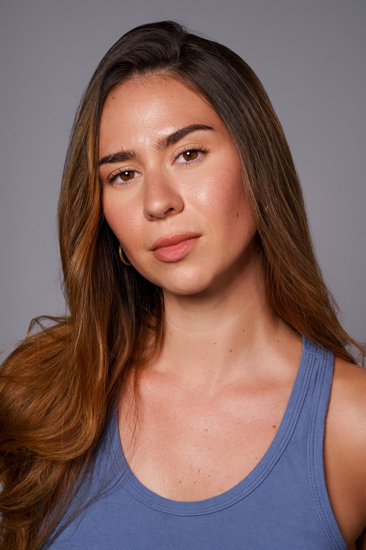 Headshot in blue tank top, hair down, serious expression